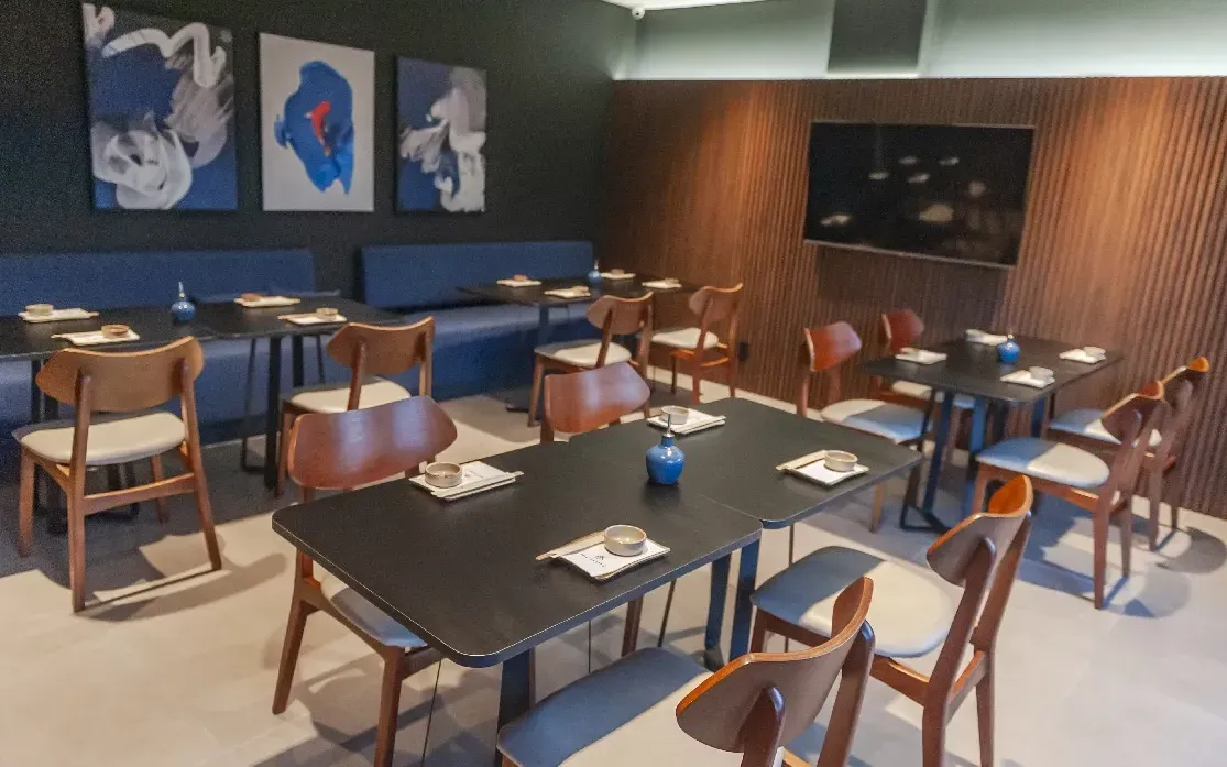 Restaurante corporativo entregue pela Ommbo, mesas de tampo escuro, cadeiras de madeira e bancos estofados em azul